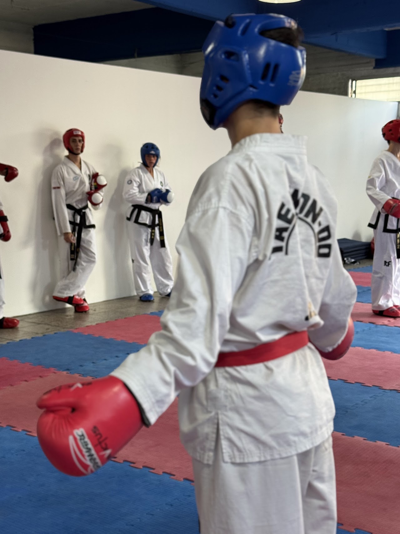 Sparring con protecciones entre alumnos de Taekwondo en MONFIT
